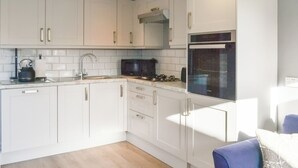 A modern kitchen with white cabinets, a stainless steel kettle, and a built-in oven. - 1 bedroom accommodation in Mablethorpe (Mablethorpe)