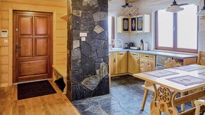 A wooden door, a stone wall, a kitchen with cabinets and a window, and a dining table with chairs. - Gorgeous home in Huba with house a mountain view (Huba)