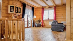 A wooden cabin interior with a wooden staircase, a grey sofa, a chair, and a window with curtains. - Gorgeous home in Huba with house a mountain view (Huba)