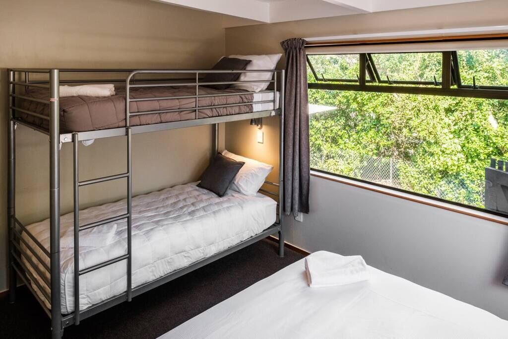 Une chambre avec un lit superposé et une fenêtre donnant sur un paysage verdoyant.