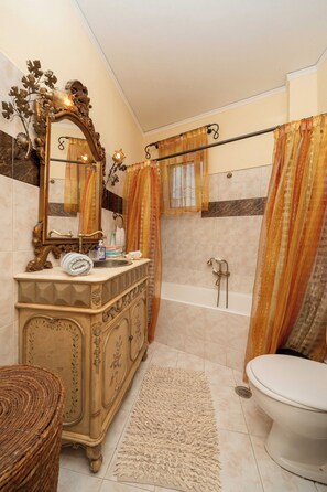 A bathroom with a vanity, a bathtub, a toilet, and a mirror. - Helena's Home (Markopoulo Mesogaias)