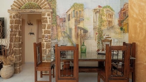 A dining area with a stone archway, wooden chairs, and a table. - Helena's Home (Markopoulo Mesogaias)