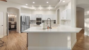 A modern kitchen with white cabinetry, a central island, and a chandelier.