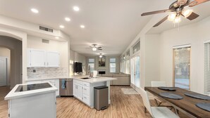 A spacious kitchen with a central island, white cabinetry, and a dining area with a long table.