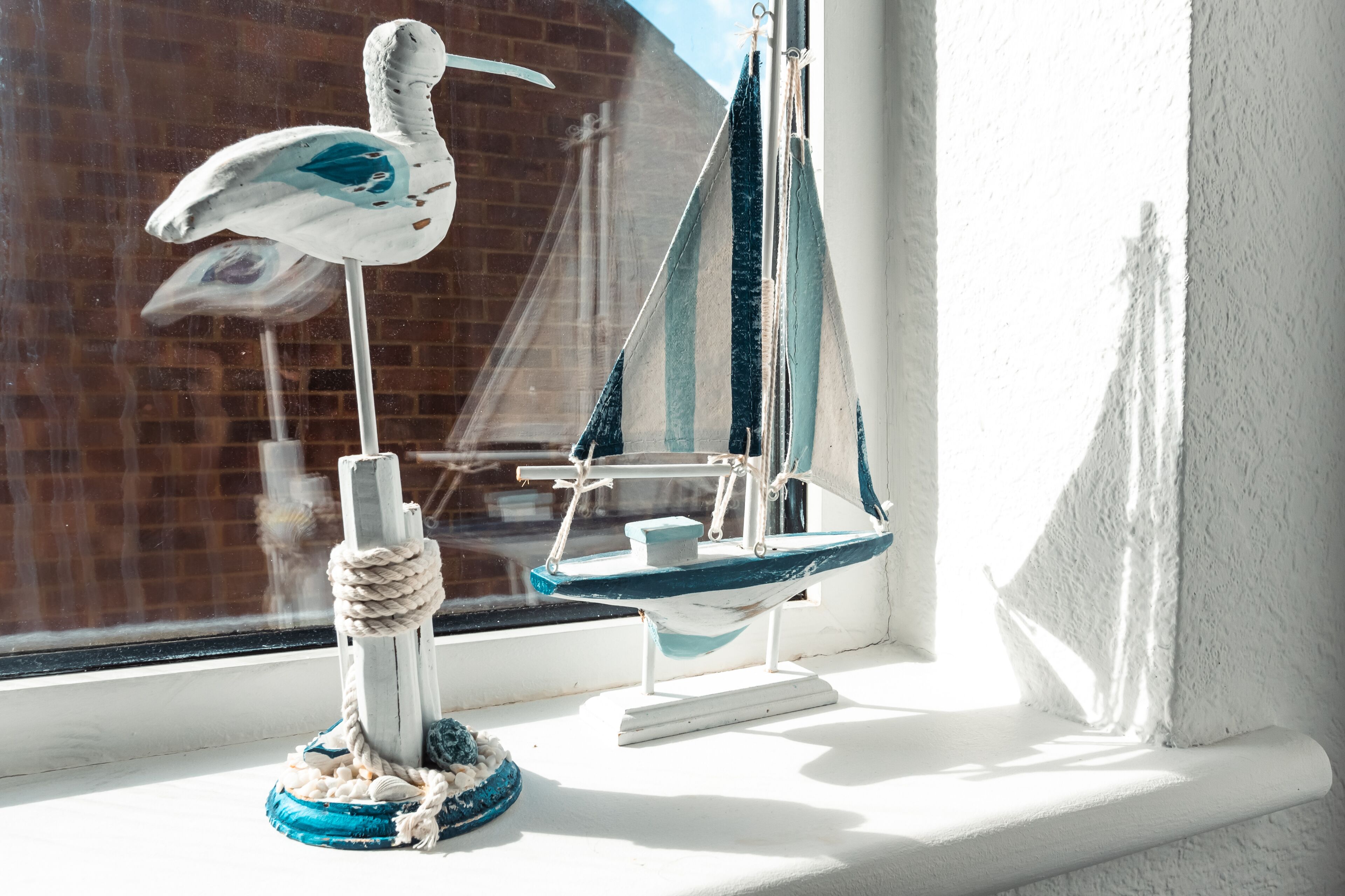 Un velero modelo y una figurita de pájaro en un alféizar.
