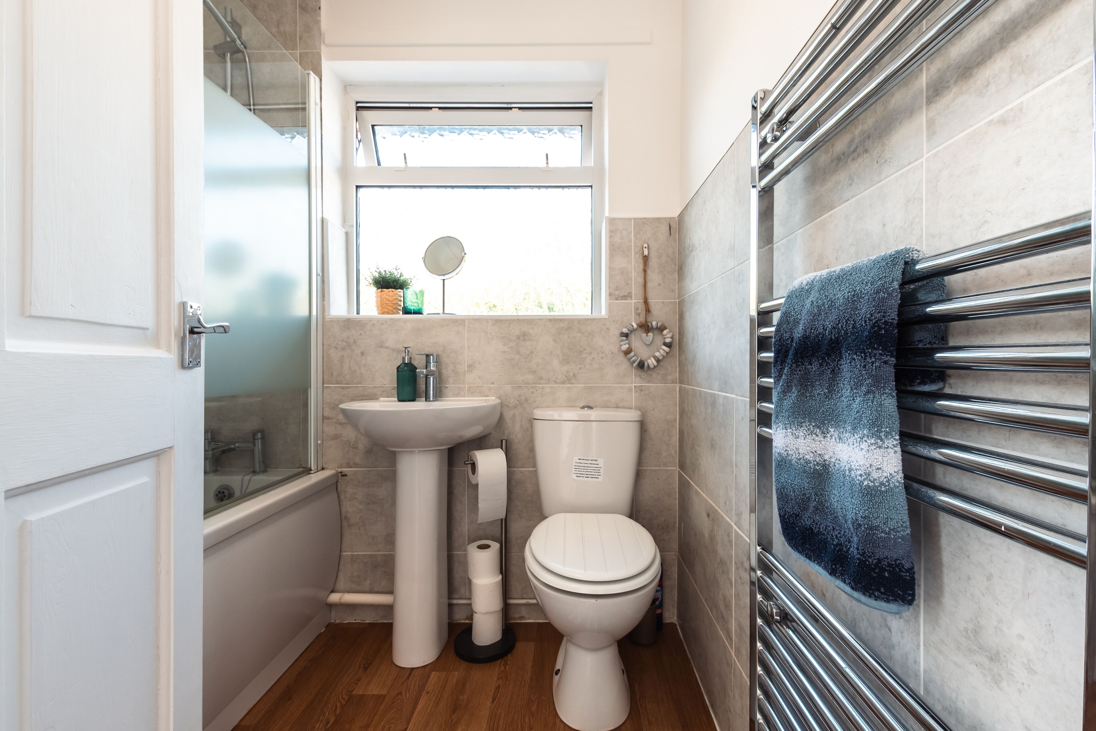 A bathroom with a bathtub, sink, toilet, and a window with a view of greenery.