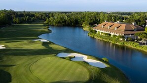 A golf course with a clubhouse adjacent to a lake.
