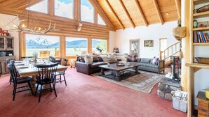 Un salon spacieux avec un haut plafond, de grandes fenêtres, un coin repas et une cheminée accueillante.