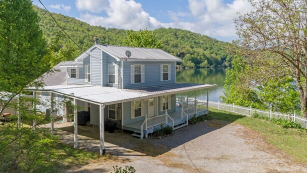 Une maison à deux étages avec un porche abrité et une vue sur un lac.