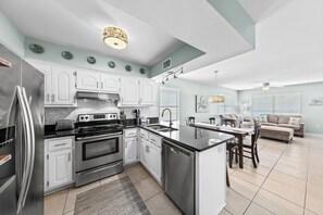 A modern kitchen with white cabinets, stainless steel appliances, and a central island. - Beach Days & Fire Nights! Family 3BR Duplex Just Steps from the Sand! (Gulf Shores)