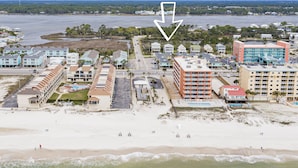 Un hotel frente al mar con varias construcciones, una playa y vistas al océano.