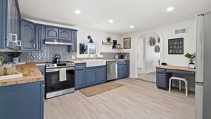 Une cuisine moderne avec des meubles gris, une cuisinière en acier inoxydable et un plan de travail en bois.