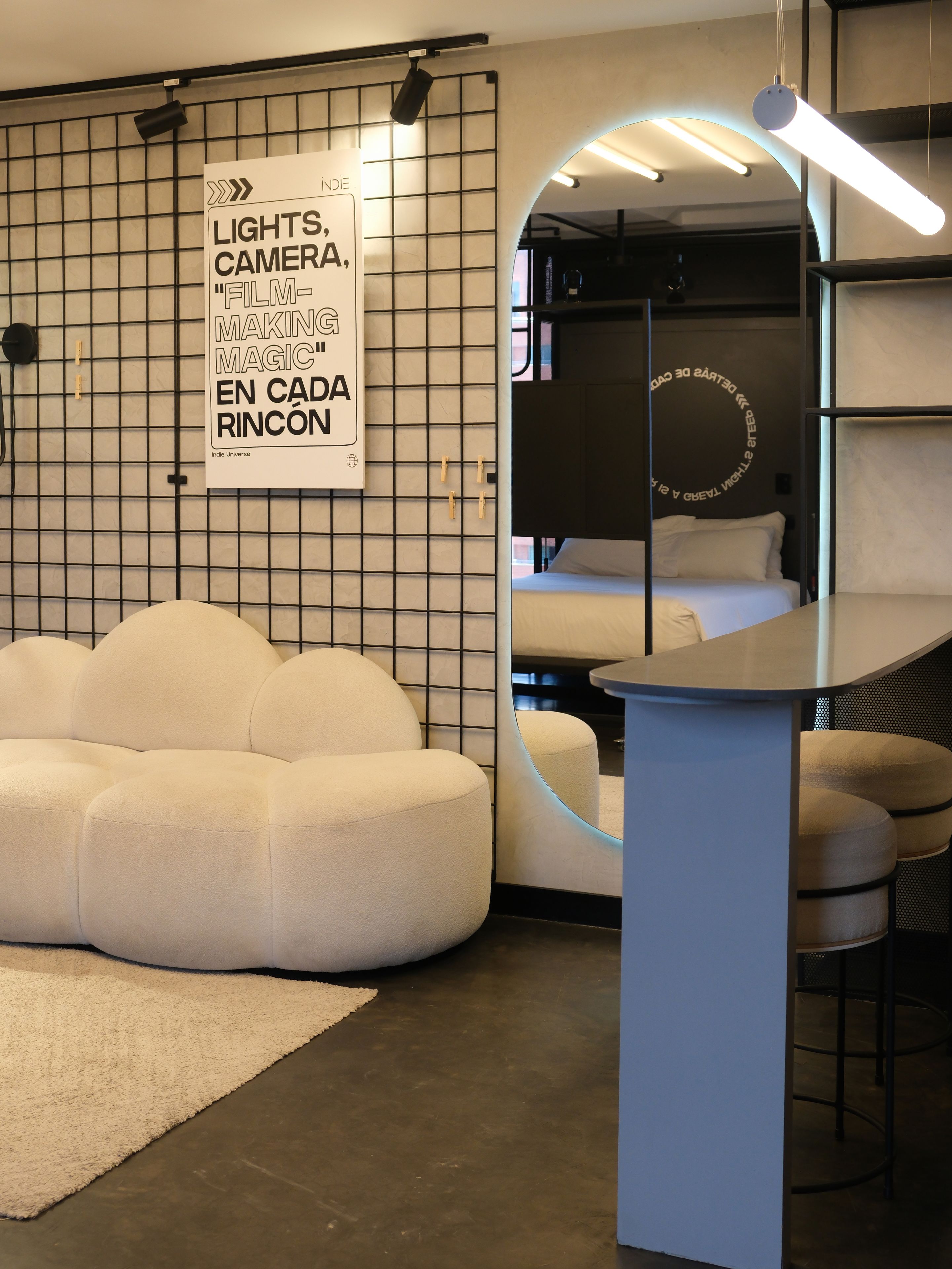 A modern room with a sofa, a circular mirror, and a poster on the wall.