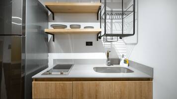 A modern kitchen with a stainless steel refrigerator, wooden cabinets, a white countertop, and a built-in sink.