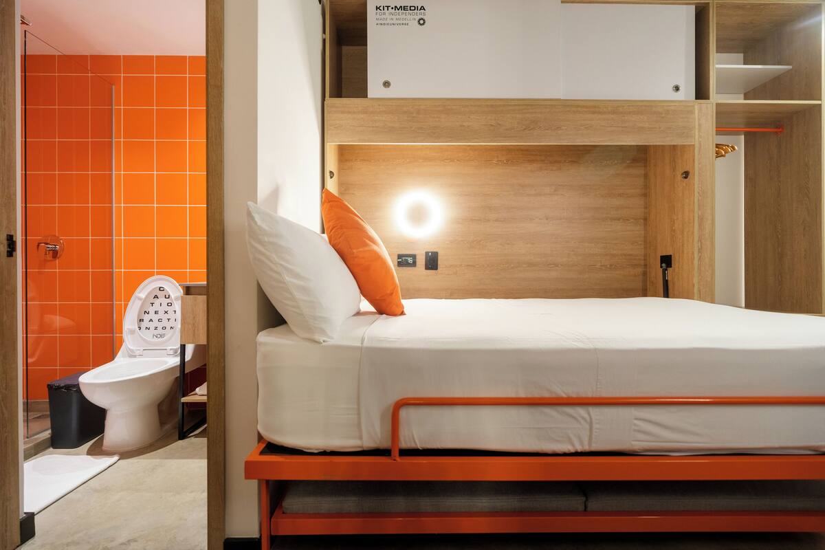 A compact room with a bunk bed, a visible toilet, and a bright orange wall.