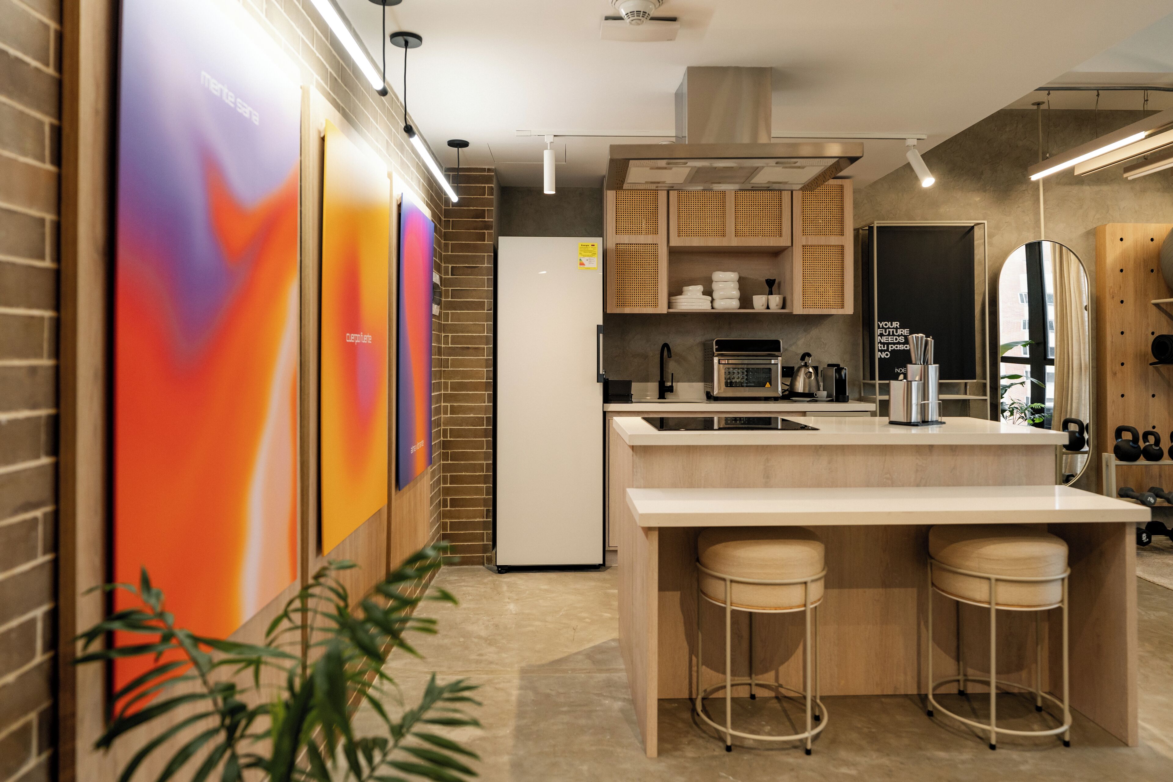 A modern kitchen with a central island, bar stools, a refrigerator, and a microwave.