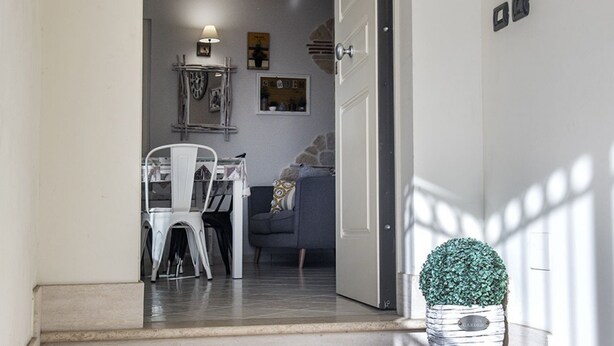 A doorway leading to a dining area with a table and chairs, a sofa, and a decorative plant. - N213 - Numana, new apartment in the center (Numana)