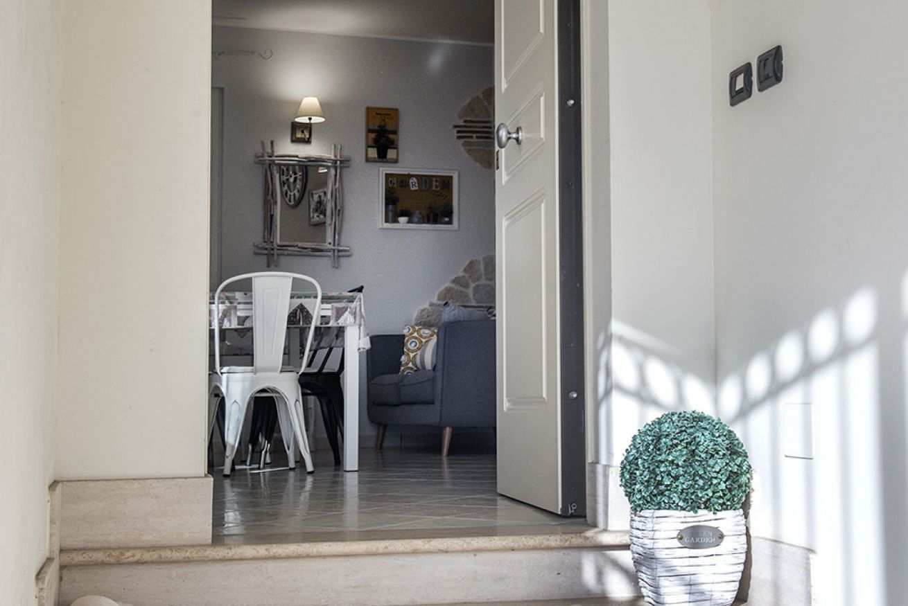 Uma porta de entrada para uma sala de jantar com uma mesa e cadeiras, um sofá e uma planta decorativa.