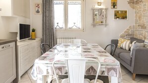 A dining area with a table set for four, a sofa, a TV, and a window with curtains. - N213 - Numana, new apartment in the center (Numana)