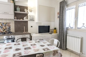 A compact kitchen with a dining area, a TV, and a window with curtains. - N213 - Numana, new apartment in the center (Numana)