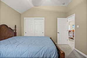 A bedroom with a bed, two white doors, and a wooden headboard.