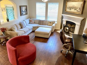 A living room with a sectional sofa, a red armchair, a fireplace, and a dining table.