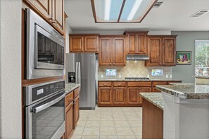 A modern kitchen with stainless steel appliances, wooden cabinets, and a large island.
