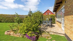 A patio with a table and chairs, a barbecue grill, and a stone wall. - Lovely home in Aakirkeby with WiFi (Aakirkeby)