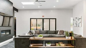 A modern living room with a grey sectional sofa, a wooden coffee table, and a built-in shelf unit. - Baxter: Pet Friendly + Private Pool/Hot Tub + Golf (Hurricane)