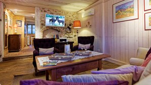 Una habitación acogedora con chimenea, televisión y una mesa con copas de vino.