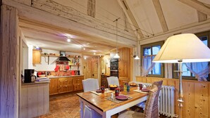 Una cocina rústica con armarios de madera, una mesa de comedor y un ventanal con cortinas.