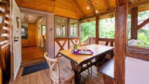 Un interior de madera con una mesa de comedor, sillas y vistas al exterior.