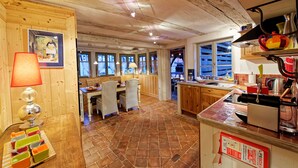 Una cocina rústica con paredes de madera, piso de baldosas y un comedor con sillas de mimbre.