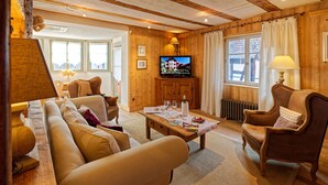 Una sala de estar acogedora con un sofá, sillones, una mesa de centro, televisor y chimenea.