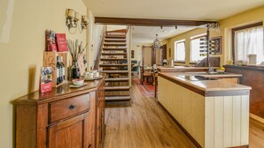 Une cuisine avec un escalier en bois, un îlot central et un coin repas avec des chaises.