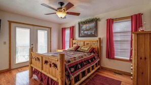 A bedroom with a wooden bed, a ceiling fan, and a window with curtains. - Mountain Villa with amazing views, Hot tub, and game room, (Marble)