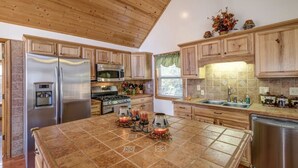 A kitchen with wooden cabinets, stainless steel appliances, a tiled island, and a window with a view. - Mountain Villa with amazing views, Hot tub, and game room, (Marble)