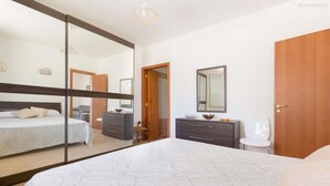 Ein Schlafzimmer mit einem großen Bett, einem Schminktisch, einem Spiegel und einer Tür.