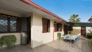 A covered patio area with a table and chairs, a door, and windows with shutters. - 981 Villa Delle Rose - Appartamento A (Porto Cesareo)