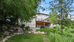 A two-story building with a balcony, surrounded by greenery and a stone wall. - Family Getaway~hot Tub, Ice Castles & Tubing Hs 5 Bedroom Home by RedAwning (Midway)