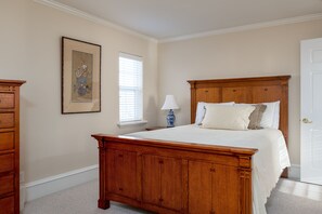 A bedroom with a wooden bed, a nightstand, a lamp, a framed picture, and a window with blinds. - Family Getaway~hot Tub, Ice Castles & Tubing Hs 5 Bedroom Home by RedAwning (Midway)