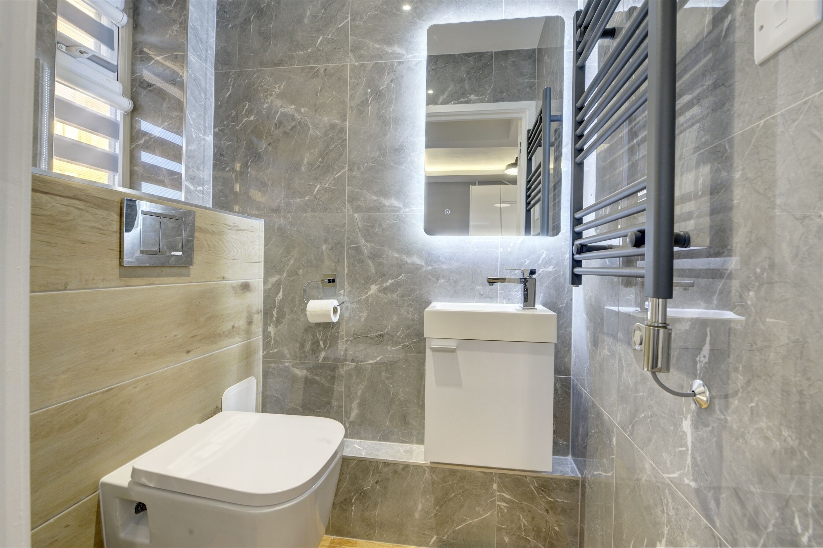 A modern bathroom with a toilet, sink, and mirror.