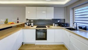 A modern kitchen with white cabinets, a granite countertop, a built-in oven, and a black sink. - Modern 2BR House & Private Parking & Kid-friendly (Rugby)