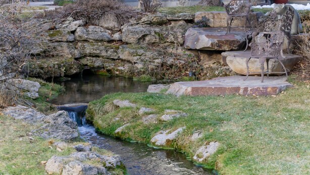 A small outdoor water feature with a stone wall and metal chairs. - Family Vacation~heated In/out Pool, Tubing & Ice Skating 719 3 Bedroom Townhouse by RedAwning (Midway)