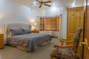 A bedroom with a bed, a chair, a nightstand, a lamp, a ceiling fan, and a wardrobe. - Family Vacation~heated In/out Pool, Tubing & Ice Skating 719 3 Bedroom Townhouse by RedAwning (Midway)