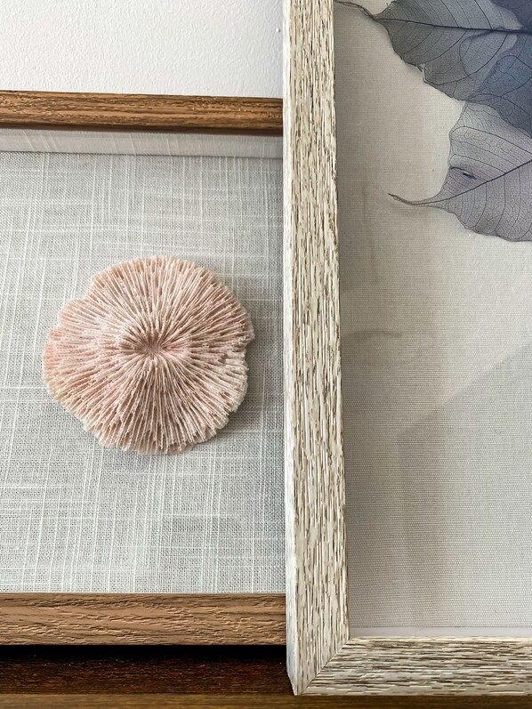 Une œuvre d’art encadrée, avec un fond en tissu texturé et un objet circulaire.