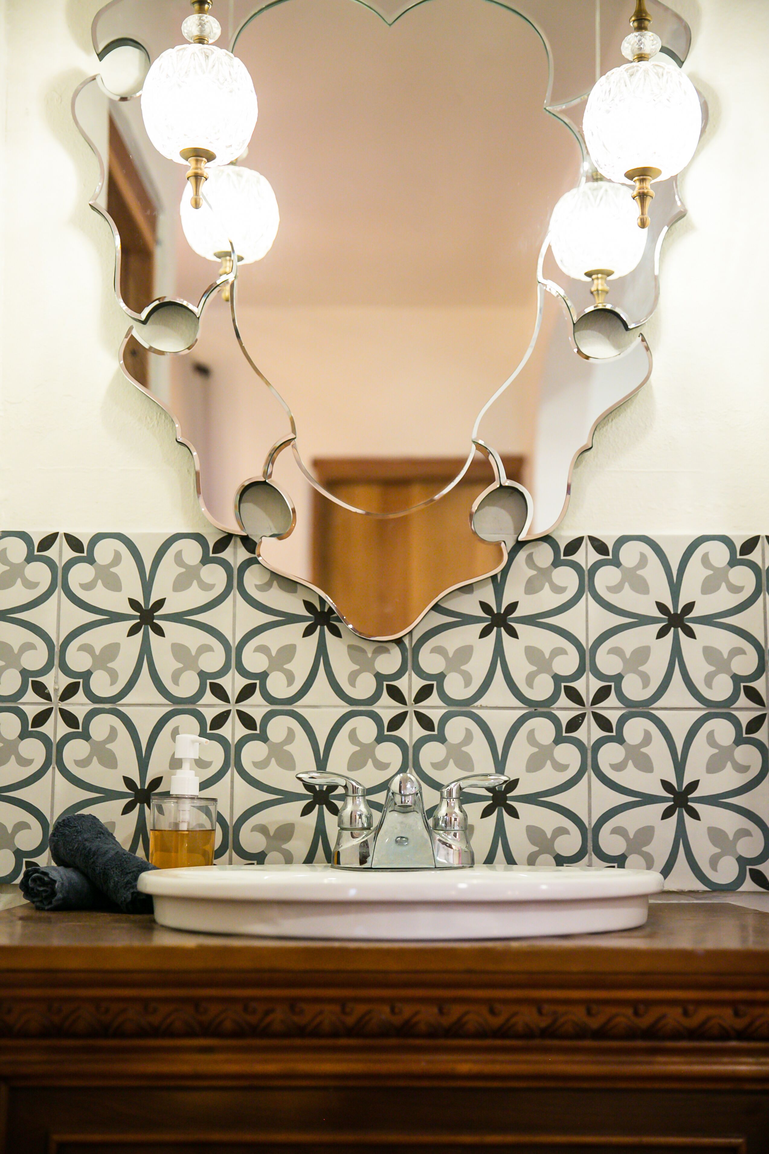 Un tocador de baño con espejo, lavabo y lámpara decorativa.