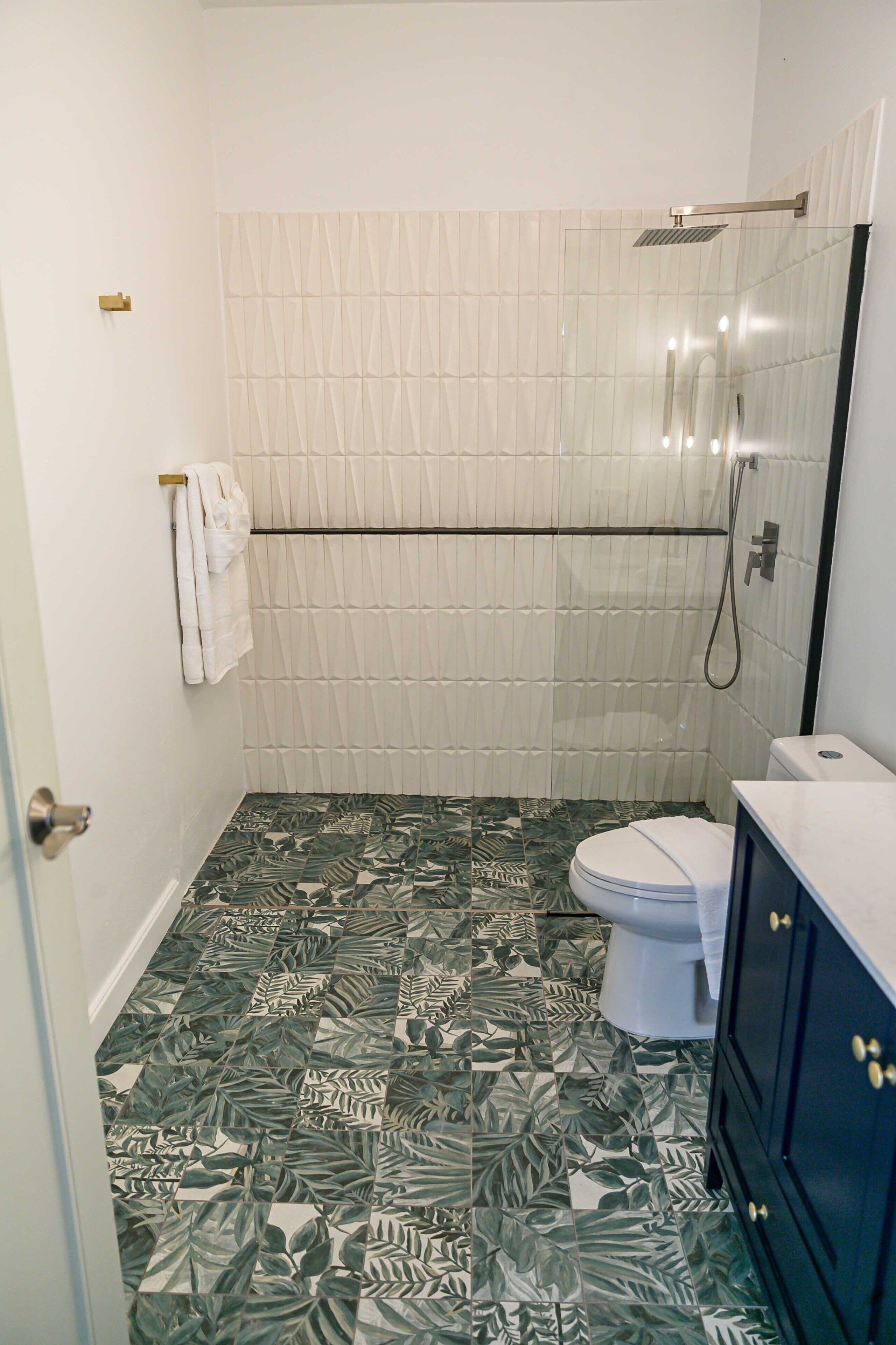 Un baño con inodoro, ducha y lavamanos con armarios oscuros.