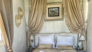 Un dormitorio con una cama grande, dos mesitas de noche, un cuadro en la pared y una cortina.