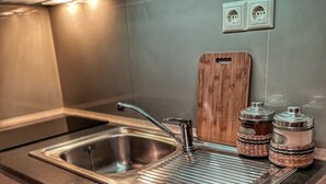 Una cocina con un lavamanos de acero inoxidable, una tabla de cortar de madera y dos saleros y pimenteros.